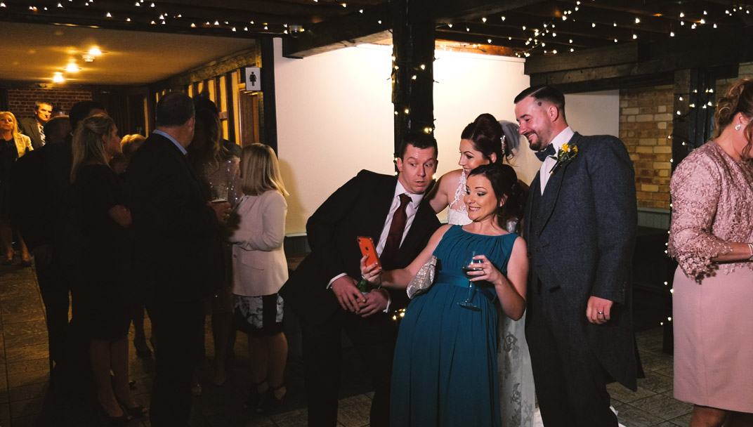 Bride and groom taking a selfie with wedding guests during a receiving line 