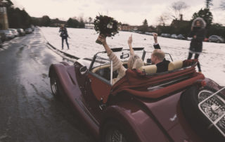 Just married couple in a car just leaving the church surrounded by snow