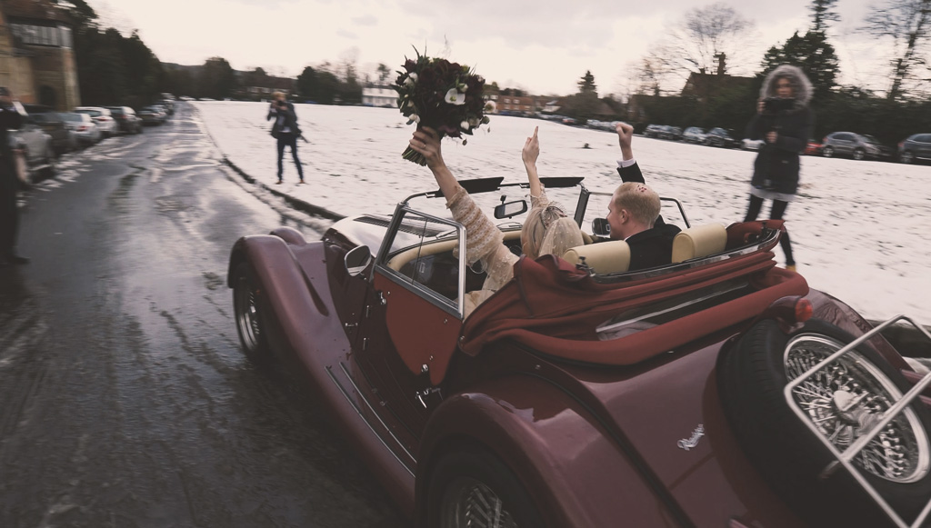 Just married couple in a car just leaving the church surrounded by snow 