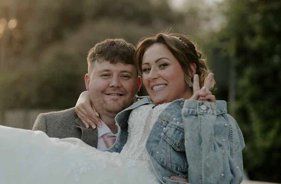Bride smiling and being lifted by groom outdoors during their wedding day